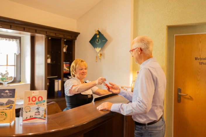Ein Mann erhält an der Rezeption einen Schlüssel von einer Frau