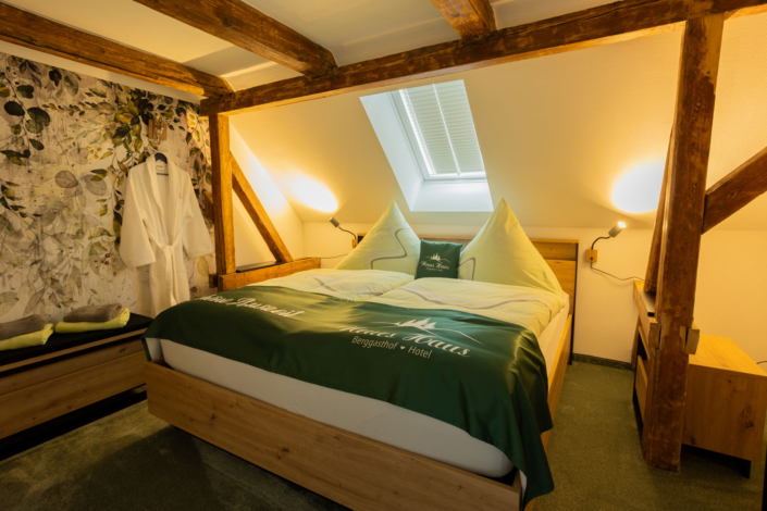 Ein Doppelbett in einem gemütlichen Dachzimmer mit Balken