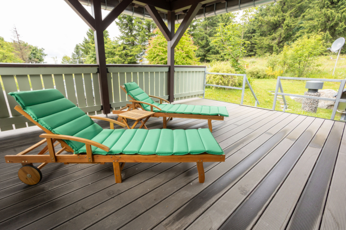 2 Sonnenliegen mit grüner Auflage auf einer Terrasse