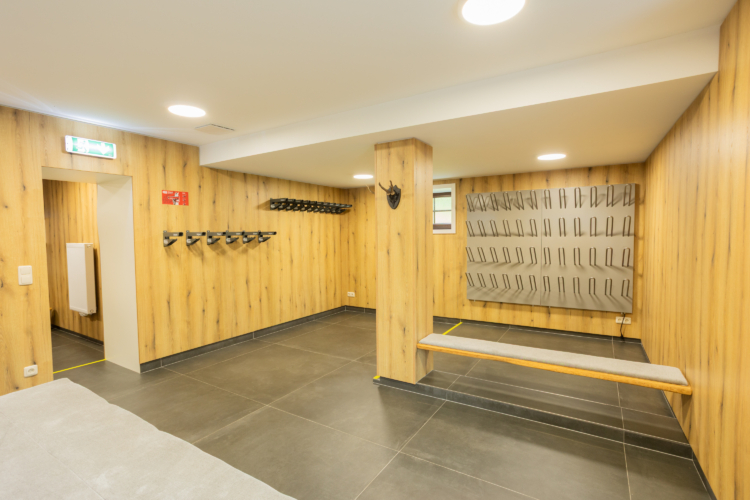 Ein heller Raum ist mit Holz verkleidet und bietet viele Haken zur Aufbewahrung von Skiern
